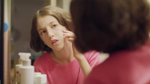 Teenager-Mädchen schaut in den Badezimmerspiegel