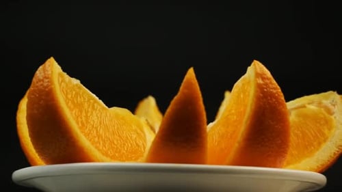 Frische Orange zum Nachtisch in einem weißen Teller auf schwarzem Hintergrund drehen Schließen