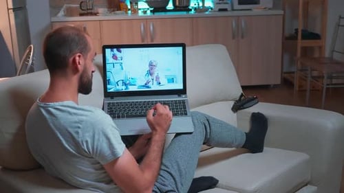 Man on Couch Telehealth Appointment With Doctor