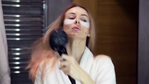 Woman Dries Hair in Bathroom Mirror