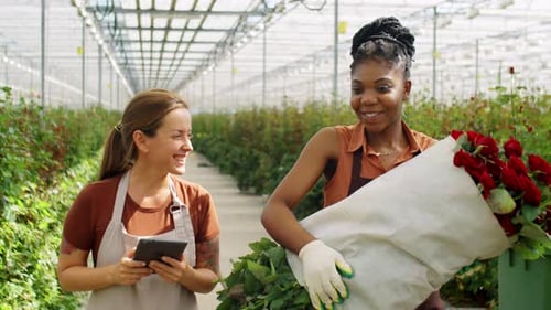 Two Women Holding Roses in Greenhouse