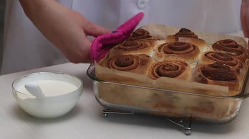 The Woman Puts On The Table A Glass Form With Ready Made Cinnabons.