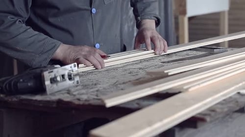Man Sawing Wooden Plank with Jigsaw at Construction Site