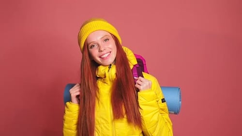 Redhaired Ginger Woman in Pink Studio Background Wearing Yellow Windbreaker Jacket with Hat and