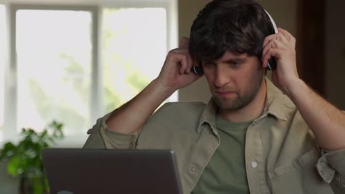 Young Man Enjoys Music With Headphones and Laptop