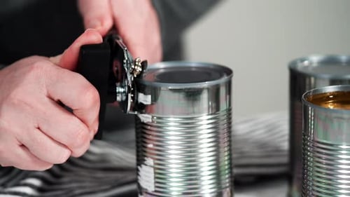 Hands open metal can with a manual can opener