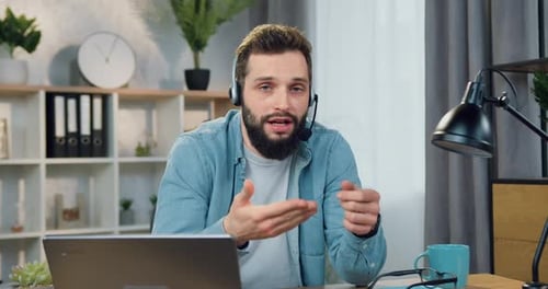 Bloguero masculino con barba elegante en auriculares grabando un vblog de estilo de vida para sus seguidores
