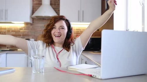 Young Woman Celebrates Success on Laptop at Home