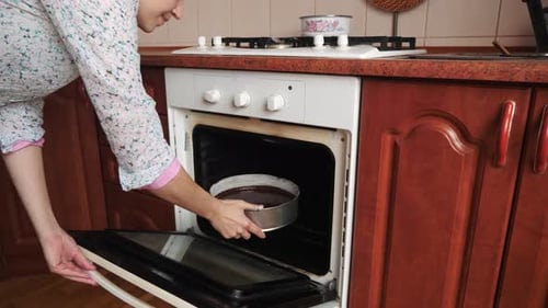 Woman Baking Cake in Oven in Home Kitchen