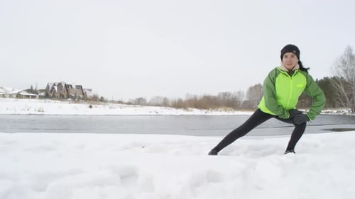 Woman Stretching on Snowy Lakefront in Winter