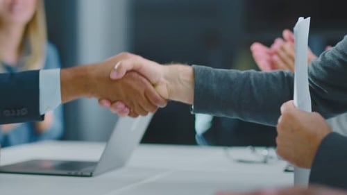 Business Handshake at Table with Applauding Colleagues