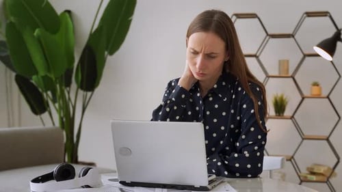 Woman Rubbing Neck While Working at Home