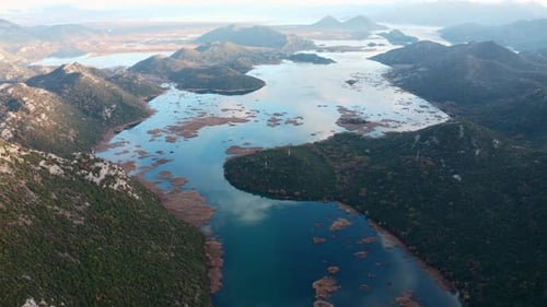 Clouds in blue sky reflected in a lake. Aerial view of the hills surrounding Crnojevica river