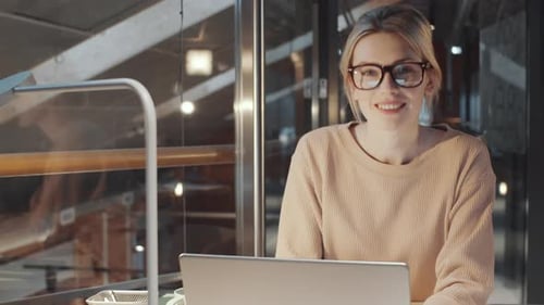 Beautiful Blonde Woman Using Laptop and Smiling at Camera at Office Workplace