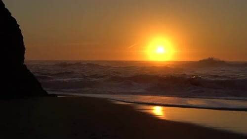 Sunset Shining Above Small Waves Crashing on the Beach