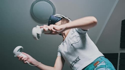 Woman with VR Headset and Controllers Playing
