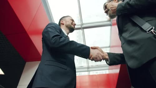 Fröhliche Männer Kollegen in Anzügen treffen sich im Bürokorridor Händeschütteln Reden