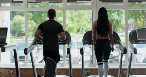 Man and Woman Exercising on Treadmills at the Gym