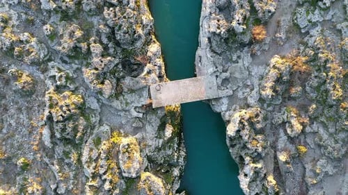 Concrete slab as a simple bridge over a narrow stream flowing through rocky desolate landscape