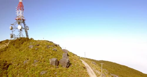 Survol aérien de la tour de transmission au sommet du mont Rochfort enveloppé de nuages bas. Localiser
