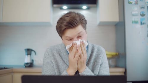 Adult Blowing Nose with Tissue in Kitchen
