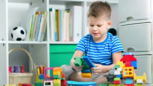 A Creative Boy is Making a Toy with a Plastic Building Kit