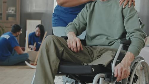 Volunteers Helping Man in Wheelchair Assemble Chair