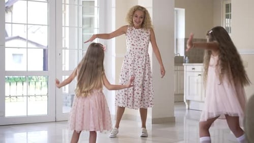 Beautiful Happy Mother Dancing with Daughters in Living Room at Home Indoors