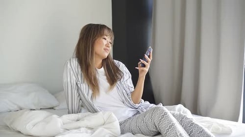 Woman Using Smartphone While Relaxing on Bed