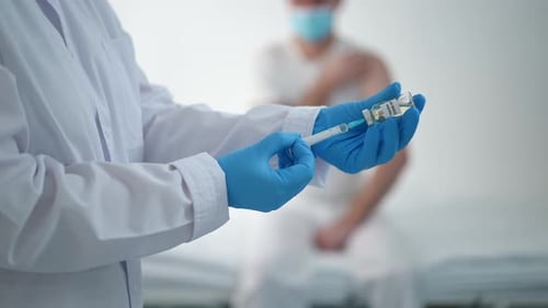 Doctor Draws Vaccine into Syringe in Hospital Setting
