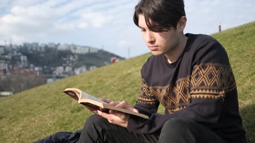 Mann liest Roman auf Park
