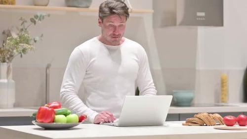 Man Working at Laptop in Modern Kitchen