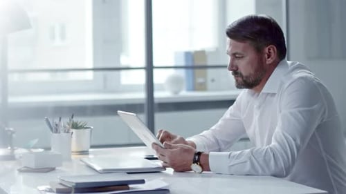 Geschäftsmann mittleren Alters surft auf Tablet im Internet