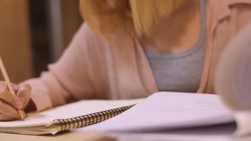 Junges Mädchen im Grundstudium macht Hausaufgaben, liest Lehrbücher und lernt fleißig, um Wissen am Hörpult zu erlangen.