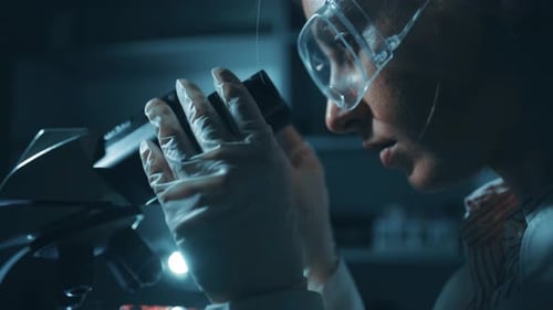 Scientist Adjusting a Microscope in a Lab