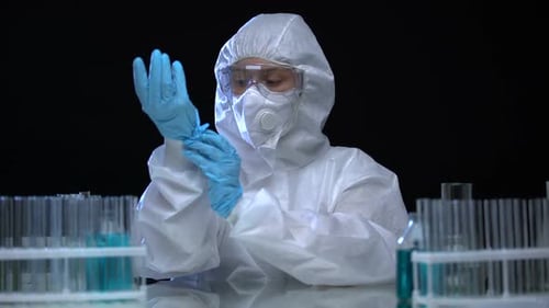 Laborassistent trägt Schutzanzug und untersucht Reagenzgläser mit Virus