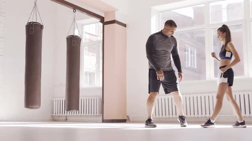 An Attractive Young Boxer Teaches His Girlfriend Boxing Techniques in a Loft Equipped for Boxing