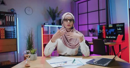 Empresaria con hiyab que lleva auriculares durante la grabación de un vídeo para un canal de Internet