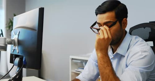 Man Thinking at Computer in Office Environment