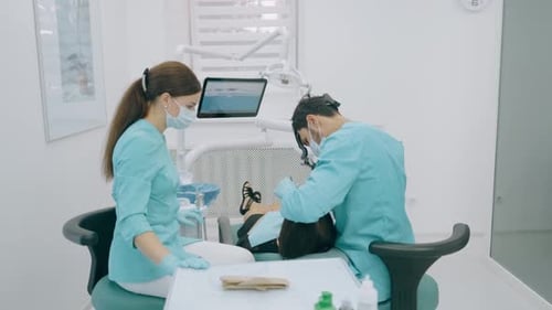 Dentist with Nurse and Patient in Dentist Office. A Patient Getting Dental Treatment at Dental
