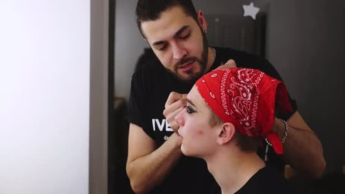 Male visagist use cosmetics for actor theatre. Stylish makeup face man backstage