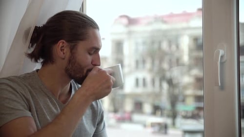 Man Drinking Coffee And Enjoying View From Window