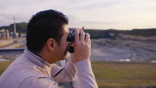 Young Adult Using Binoculars Overlooking Cityscape
