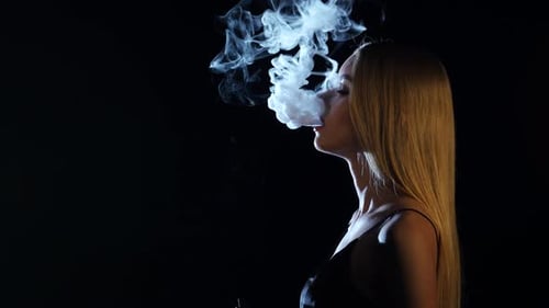 Woman Exhales Vapor Cloud in Dark Studio Woman Exhales Vapor Cloud in Dark Studio