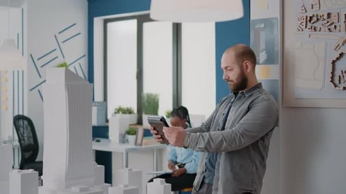 Architekt analysiert Gebäudemodell auf digitalem Tablet zur Planung von Bauplänen für den Bauplan