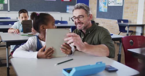 Teacher Helping Student with Tablet in Classroom