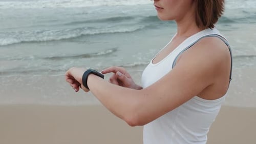 Woman Running on Beach Checking Smart Watch
