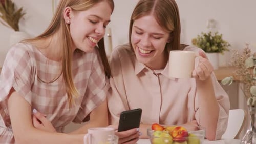 Two Young Women Looking at Smartphone and Smiling