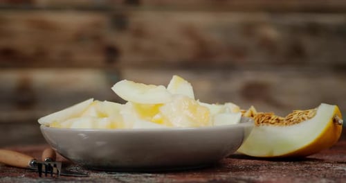 Des morceaux de melon mûr parfumé sur l'assiette pivotent lentement.