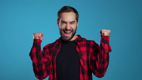 Excited Man Celebrates Success Against Blue Background
